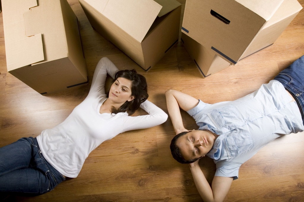 Rekordowa ilości mieszkań oddanych do użytku - kobieta i mężczyzna leża na podłodze obok kartonów. 