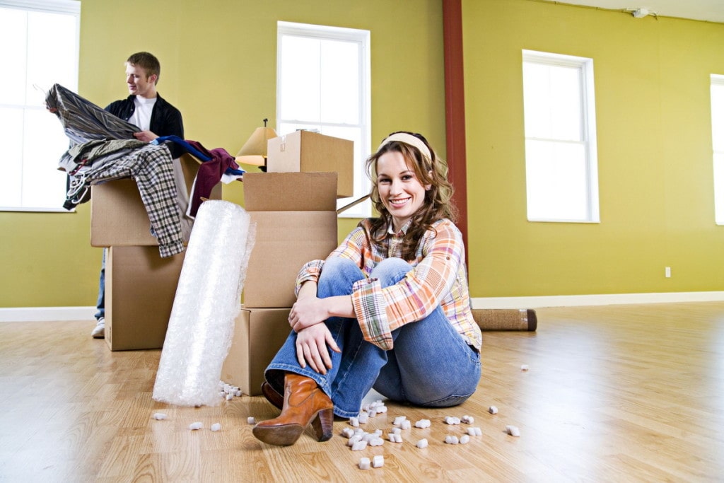 Planujesz kupić mieszkanie na kredyt w 2022 r.? O tych zmianach musisz koniecznie wiedzieć! - kobieta siedzi na podłodze w nowym mieszkaniu obok kartonowych pudełek. 