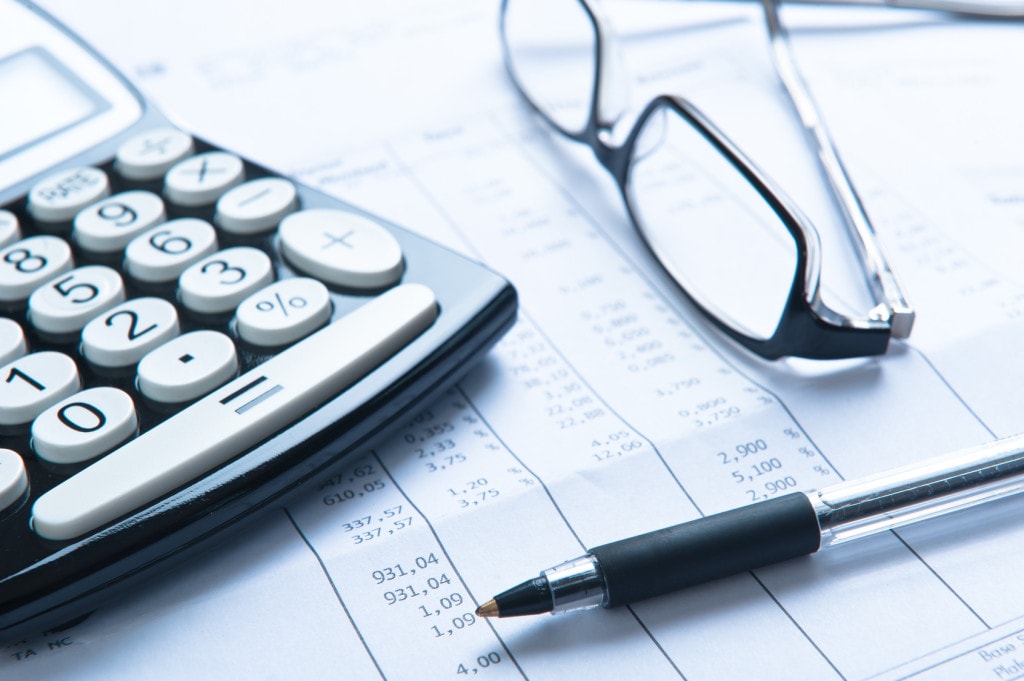 Płynność finansowa firmy a skutki COVID-19. 8 kroków do zdrowej firmy - kalkulator, okulary i dokumenty finansowe leża na stole