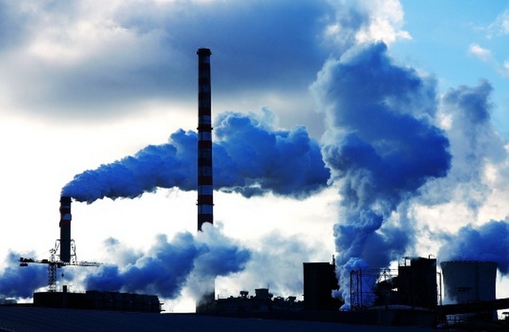 Jak kryzys klimatyczny wpłynie na nasz oszczędności i inwestycje? - dym unosi się z kominów fabryki. 