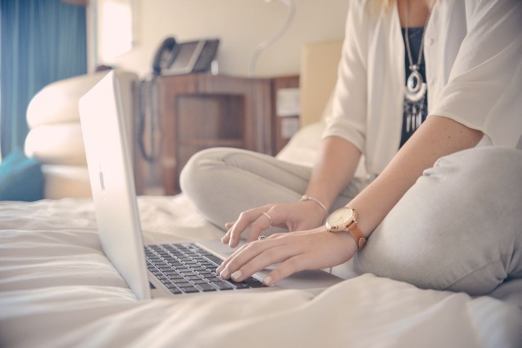 Ranking: 10 najbardziej oryginalnych zrzutek w 2021 roku - kobieta siedzi na łóżku i pisze na klawiaturze laptopa.