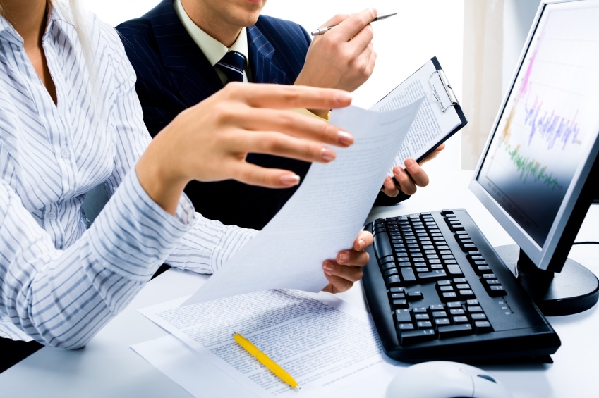Kodeks pracy po nowemu - kobieta i mężczyzna siedzą przed komputerem z dokumentami w dłoniach. 