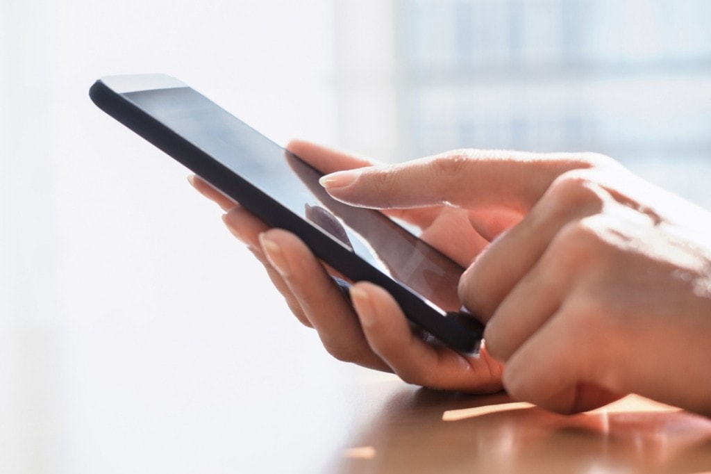 Nowe technologie dla Twojego zdrowia, czyli Internet rzeczy- kobieta z telefonem w ręku szuka aplikacji