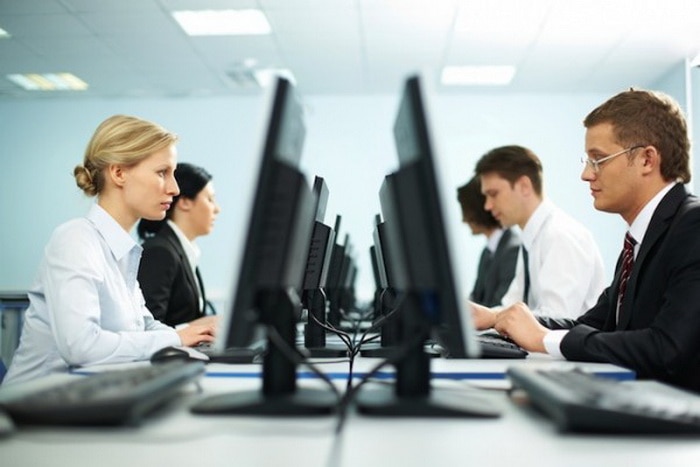 MŚP - pracownika nie zwolnię od zaraz-kobiety i mężczyżni siedzą na przeciwko siebie przy stole przed monitorami komputerów.