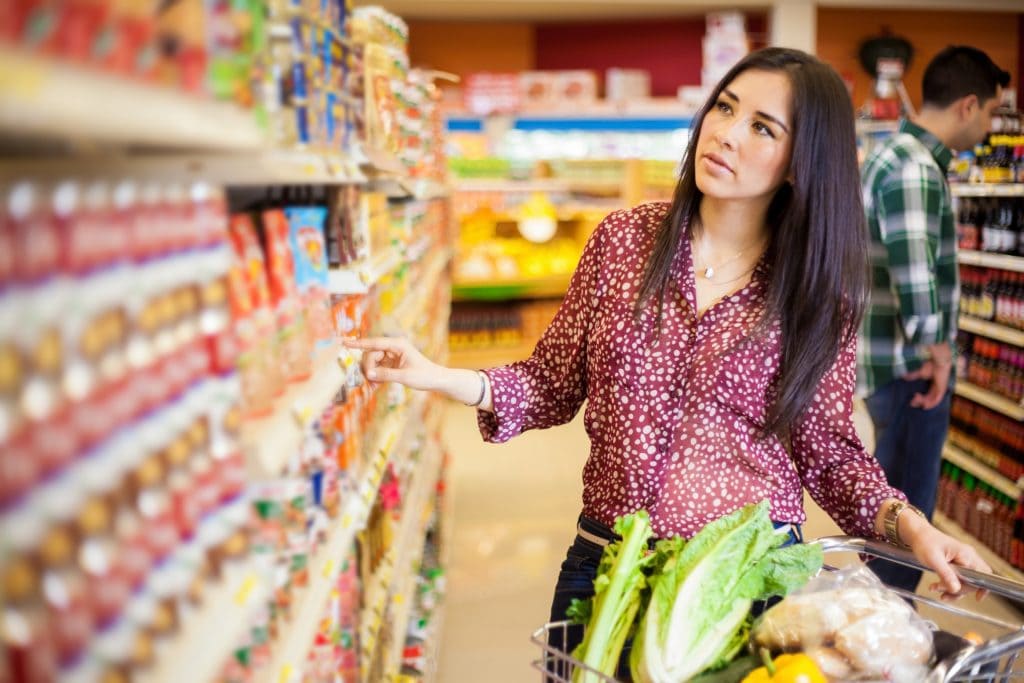 Zmiana nawyków, czyli czego nauczył nas koronawirus - kobieta robi zakupy w supermarkecie, stoi obok koszyka pełnego towaru. 