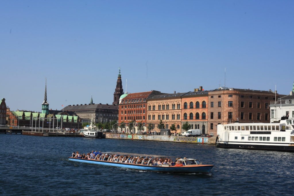 Dobre rozwiązania dla turystyki gwarantuje TFZ - statek płynie po rzece w ludźmi w środku, w tle stare miasto.