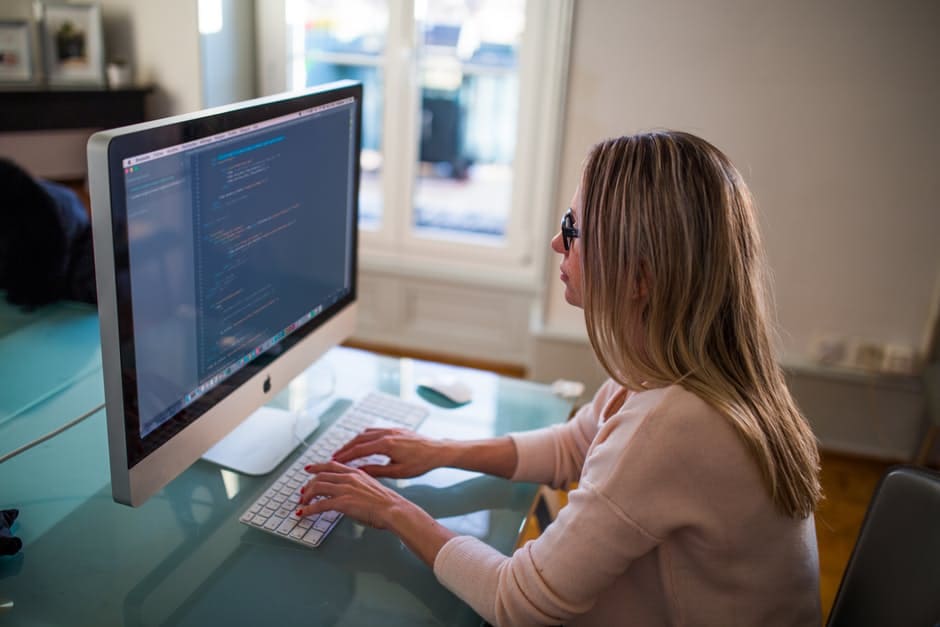 Home office zwiększa efektywność, ale wydłuża czas pracy - kobieta siedzi przy biurku i pisze na klawiaturze komputera.