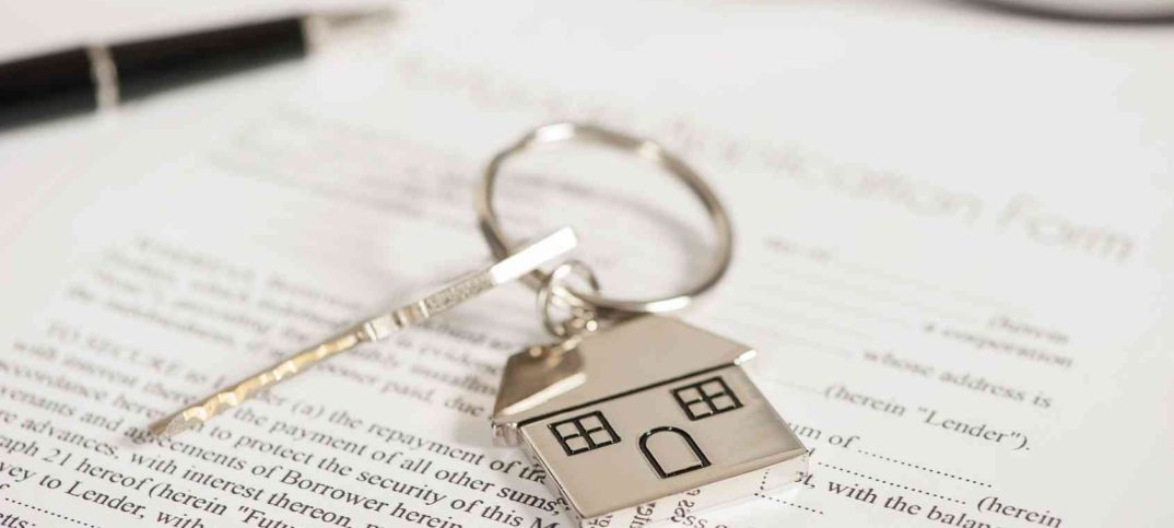 breloczek w kształcie domu przy kluczach na umowie wynajmu