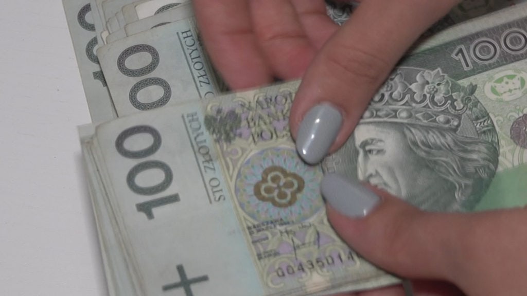 Polski Ład – pensje pracowników -banknoty 100 złotowe w damskich dłoniach.