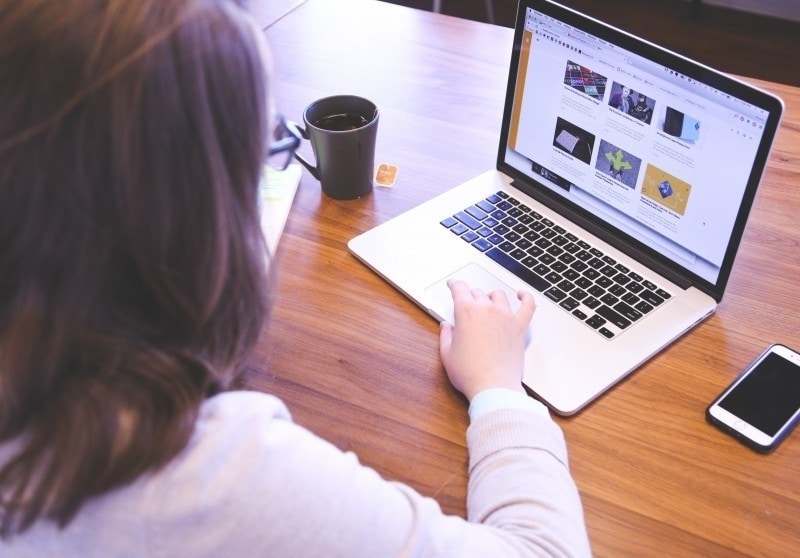 Jakich zakupów najczęściej dokonujemy przez internet? - kobieta siedzi przed otwartym laptopem. 