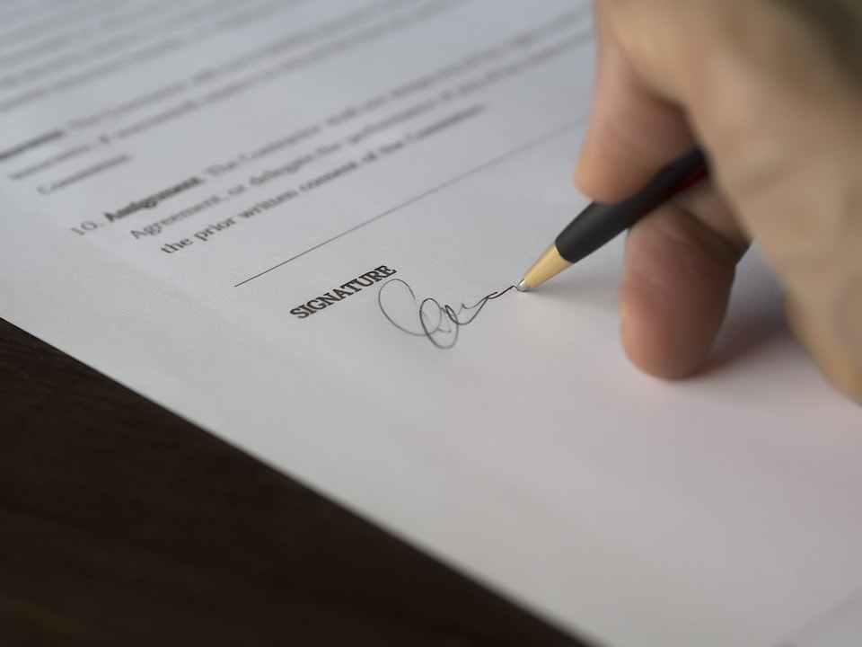 BIK o rynku pożyczkowym- męska dłoń trzyma długopis w reku i podpisuje dokument. 