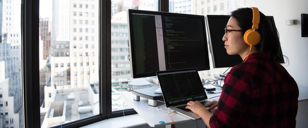 Firmy IT odporne na kryzys - kobieta siedzi przy biurku przed ekranami  komputera.