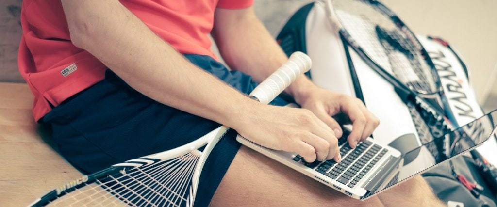 Otwarta bankowość, czyli szybszy proces potwierdzania tożsamości klienta - mężczyzna siedzi na sali treningowej i pisze na klawiaturze laptopa.