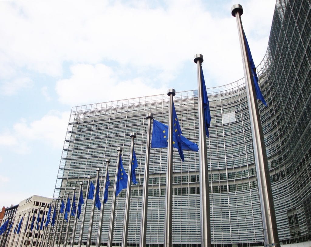 KE zaostrza walkę z praniem pieniędzy i finansowaniem terroryzmu-budynek Komisji Europejskiej w Brukseli, widok z zewnątrz, flagi UE falują na wietrze
