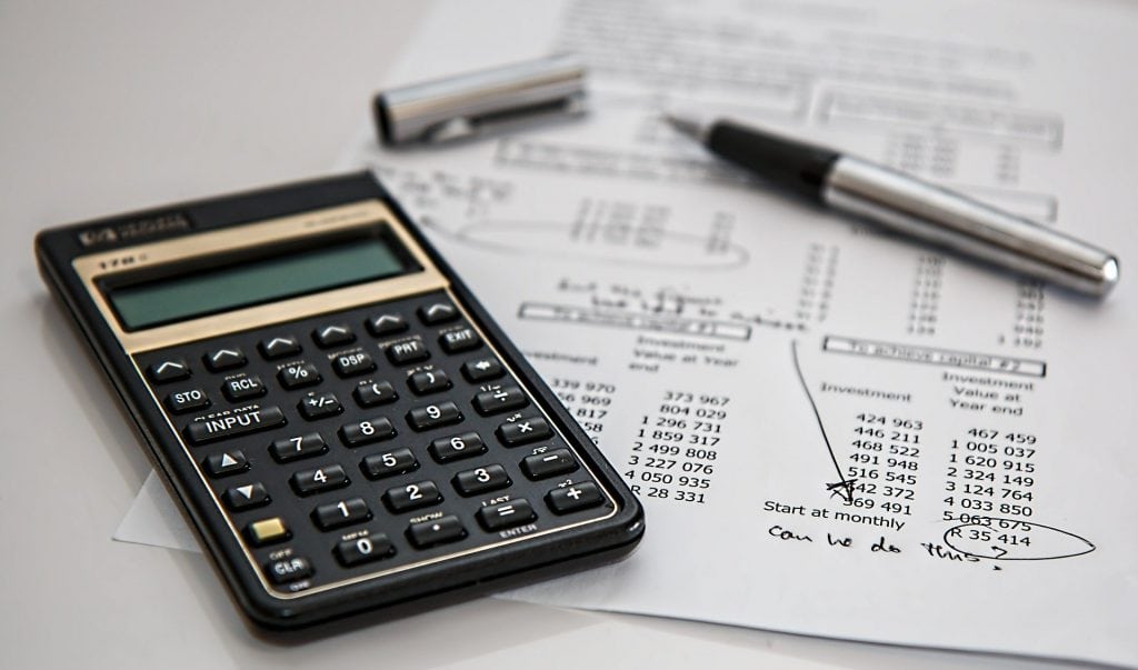 Koszty pozyskania kapitału. Jakie finansowania wybrać? - kalkulator, dokumenty i długopis leżą na biurku 