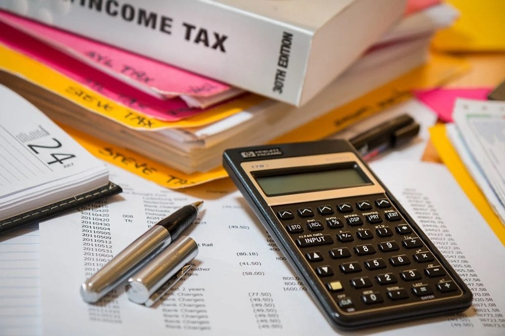 Rada Przedsiębiorczości apeluje o zmiany w podatku bankowym - dokumenty, książki, kalkulator i długopis leża na stole.