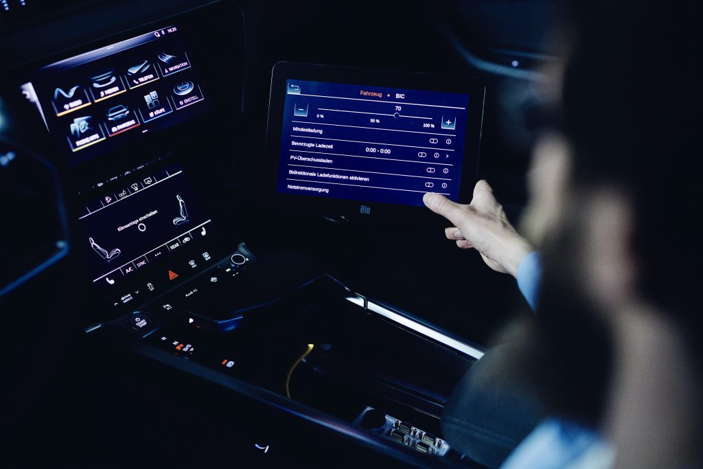 Samochody elektryczne Audi to część transformacji energetycznej - wnętrze samochodu, eka mężczyzny steruje aplikacjami na telebimie. 