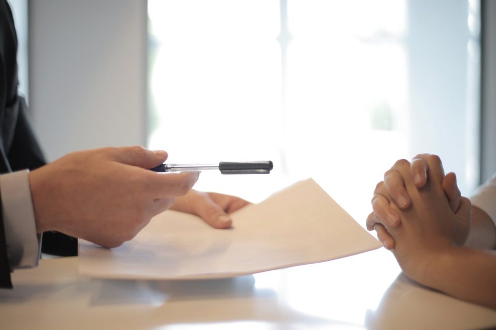 5 ważnych pytań o kredyt hipoteczny dla przedsiębiorców - dłonie męskie podają notes i długopis dłoniom damskim. 