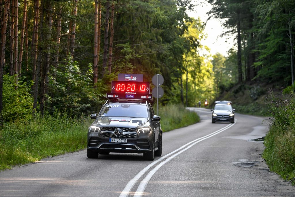 Hybrydowe Mercedesy wspierają Enea IRONMAN 70.3 Gdynia -auto Mercedes Benz na leśnej drodze.