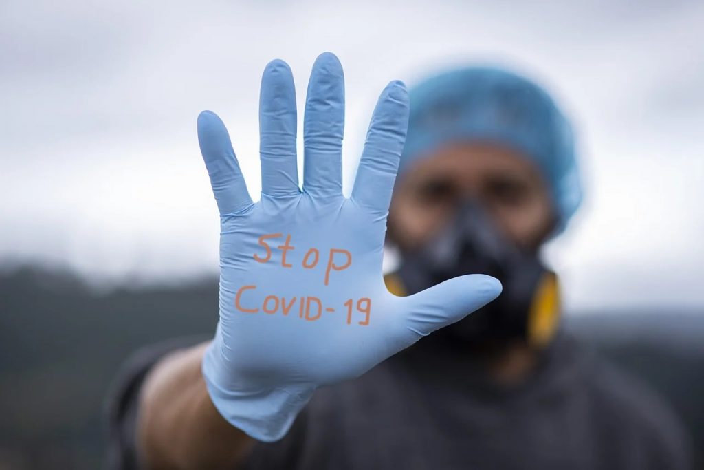Koronawirus - jak sobie radzić z lękiem?- meżczyzna pokazuje dłoń w rękawiczce z napisem stop covid-19
