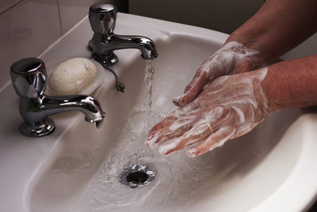 Nawyki w pracy zwalczą COVID-19 - mężczyzna myje ręce