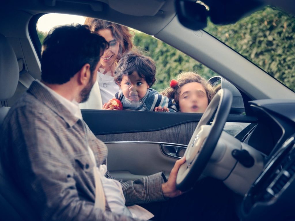 Volvo Cars Family Bond – nowy 24-tygodniowy urlop rodzicielski dla pracowników - meżczyzna siedzi  w aucie, za szybą machają dzieci i kobieta