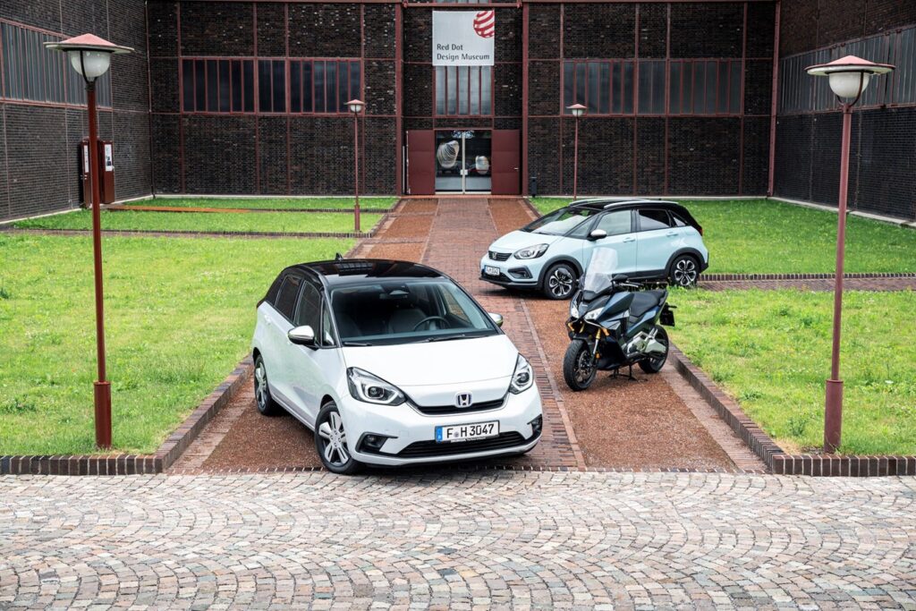 Honda największym producentem silników na świecie - na trawie przed budynkiem stoją dwa auta i motor