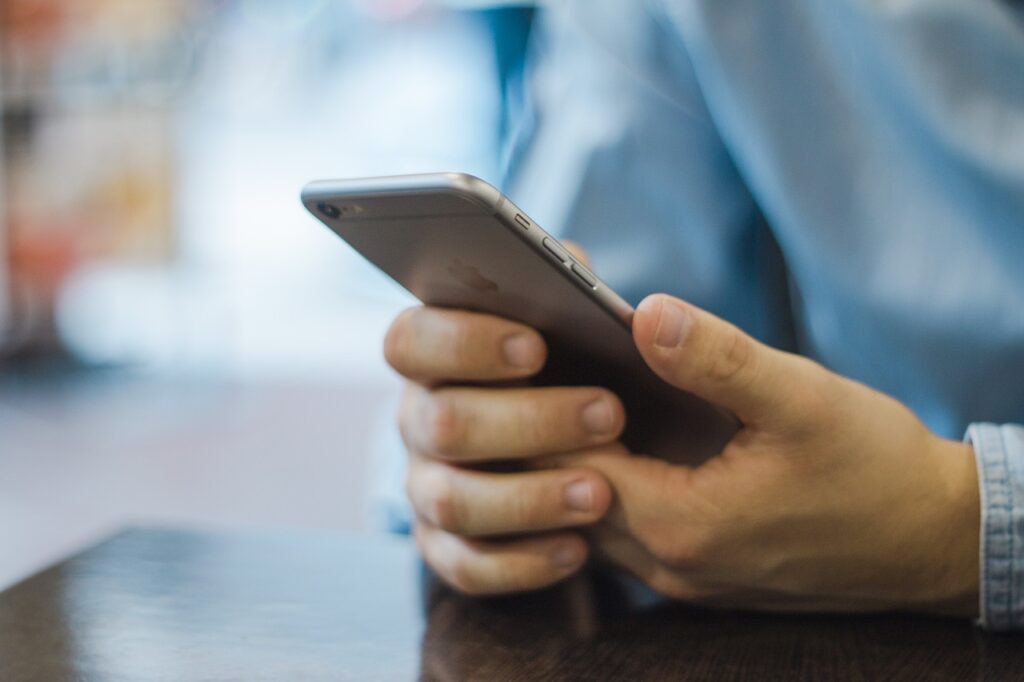 Doręczenia elektroniczne - nowe zasady od 05.10.2021 - mężczyzna trzyma w rękach telefon. 