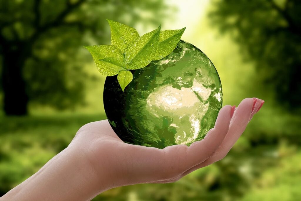 Hulajnogi elektryczne - ekologiczna mikromobilność - kobieca dłoń trzyma zieloną kule w kształcie kuli ziemskiej. 