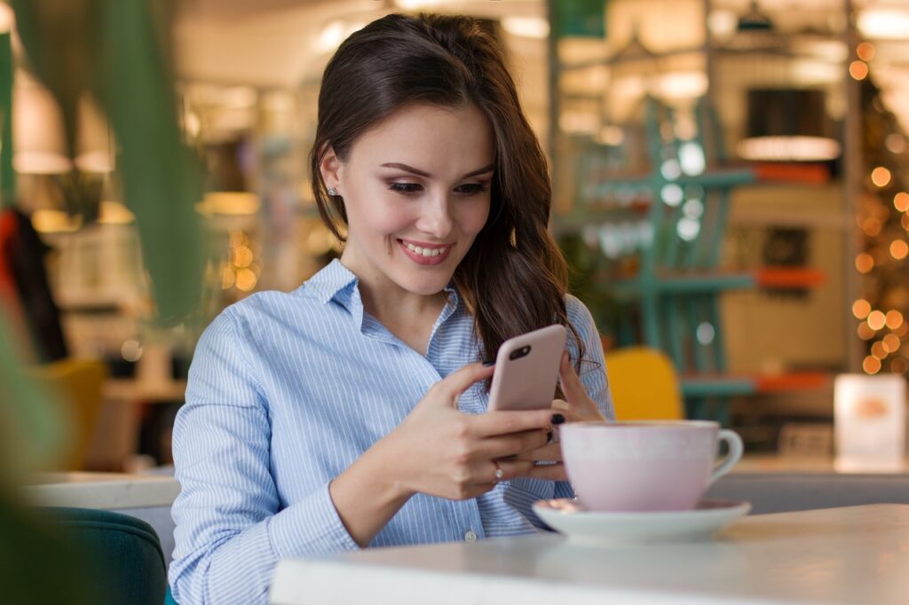 Koniec z czekaniem na rachunek w restauracjach - kobieta siedzi przy stoliku w restauracji i trzyma telefon w rękach. 