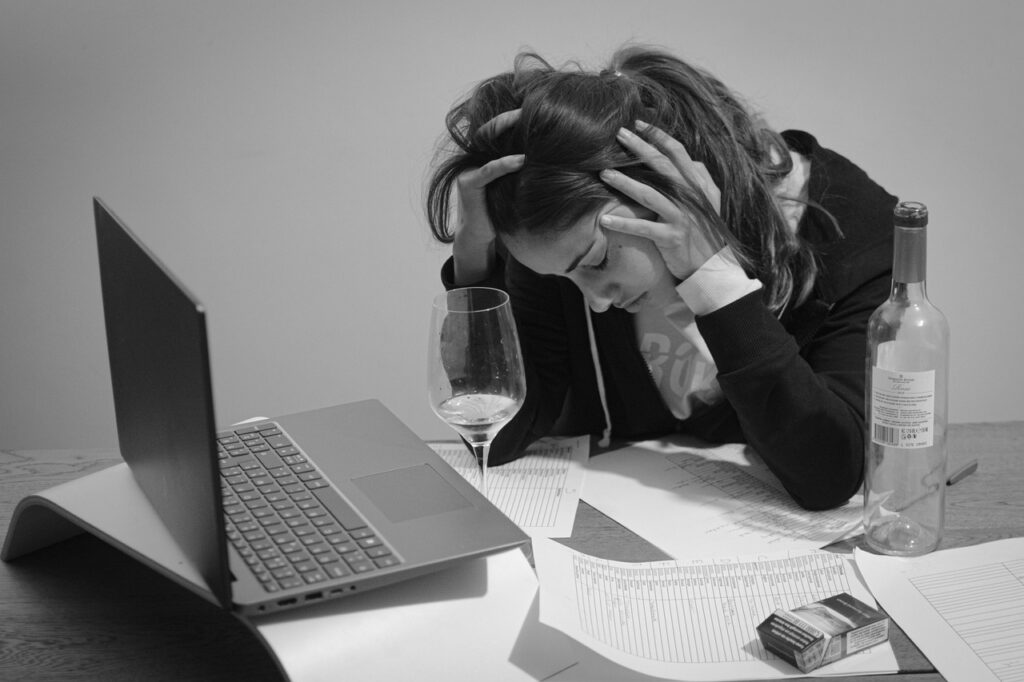 Dopuszczenie do pracy pijanego pracownika to wykroczenie - kobieta trzyma się za głowę siedząc przed komputerem. 