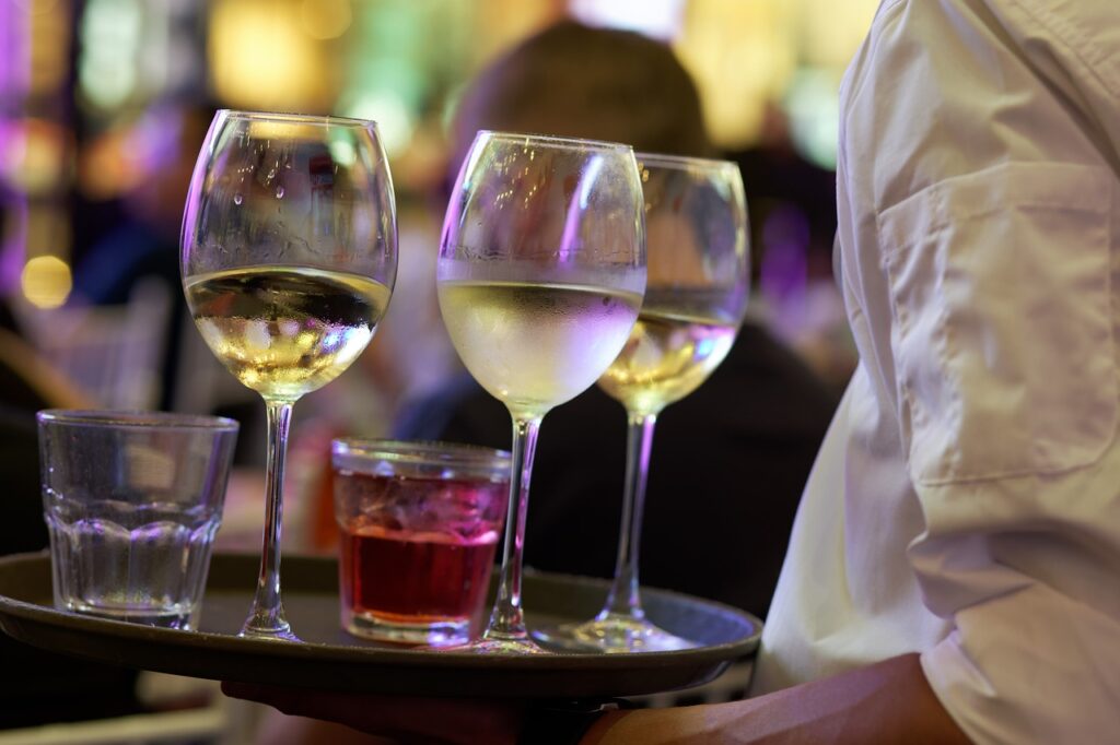 Jak pandemia wpłynęła na rynek alkoholi? - kelner niesie na tacy alkohol w kieliszkach
