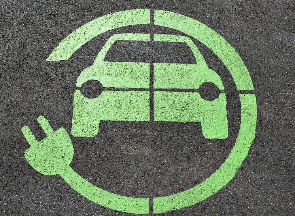 Elektromobilność w Polsce przyspiesza - Elocity podsumowuje 2021 rok - na chodniku narysowane zielone auto z wtyczką elektryczną. 