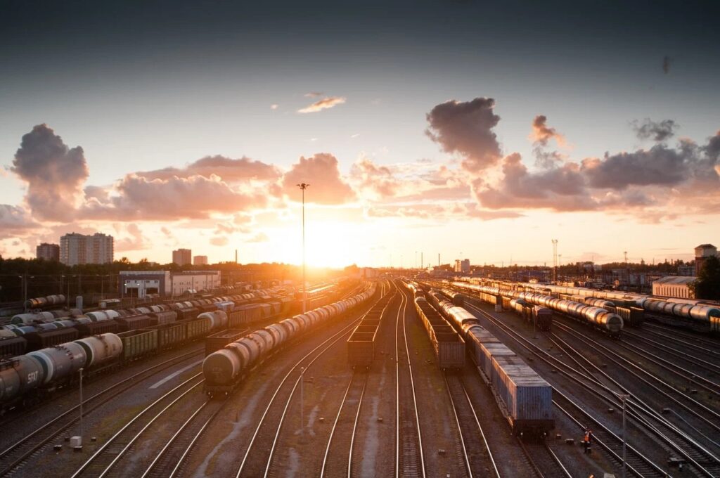 Co nas czeka na kolejowym szlaku - pociągi na torach w tle zachodzącego słońca.
