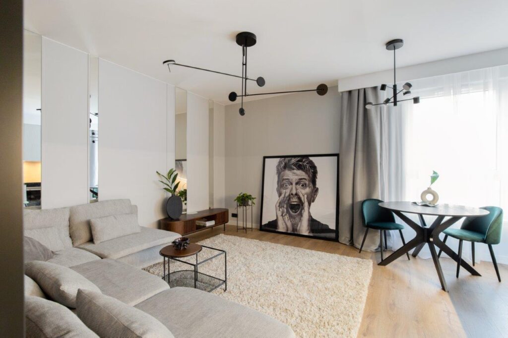 Wykończenie mieszkania pod klucz od dewelopera - dlaczego warto? - w salonie stoi kanapa , stół i krzesła, przy ścianie stoi obraz. 