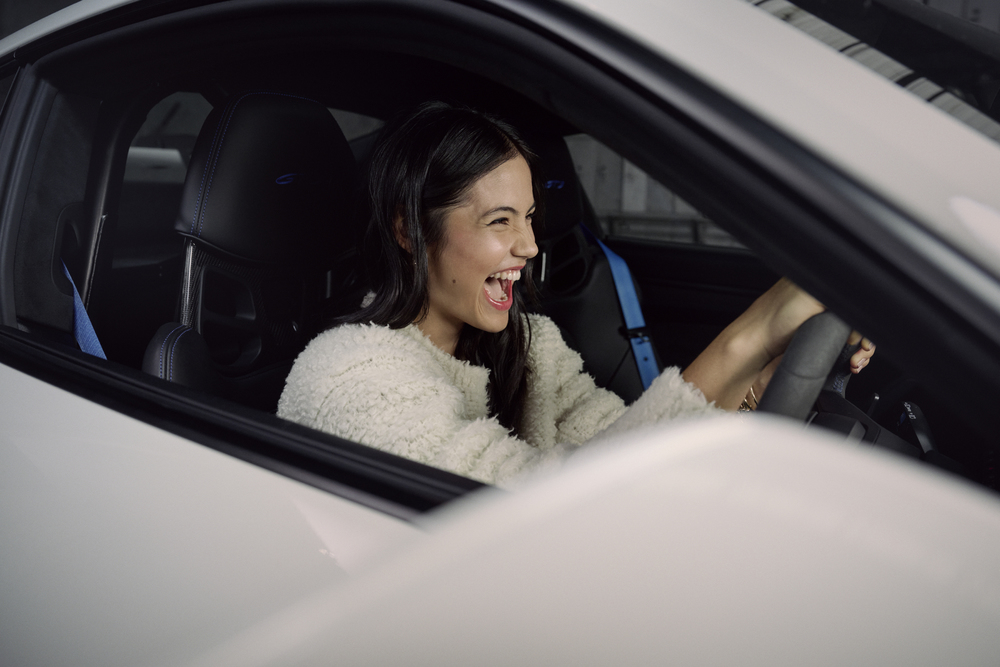 Młoda tenisistka nową ambasadorką marki Porsche - kobieta z uśmiechem na twarzy prowadzi samochód.