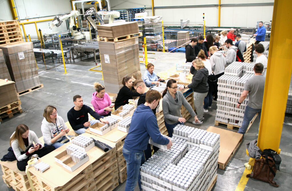Krynica Vitamin dostarczyła pomoc humanitarną do Lwowa - ludzie w fabryce naklejają etykiety na puszki. 
