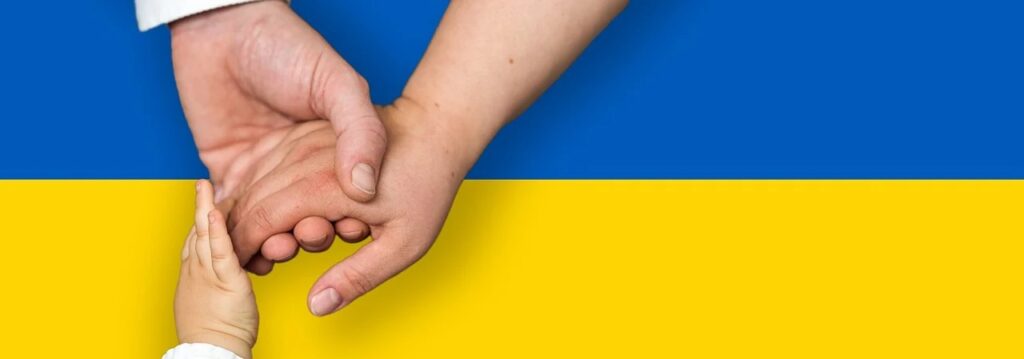 UN GCNP uruchamia system długoterminowego wsparcia dla Ukrainy - dłonie w uścisku na tle flagi Ukrainy.