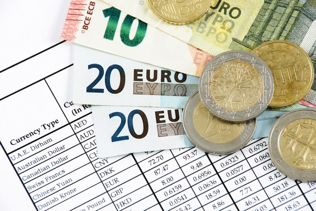 Co będzie się działo z walutami w 2023 roku? - banknoty i monety w euro leżą na dokumencie. 