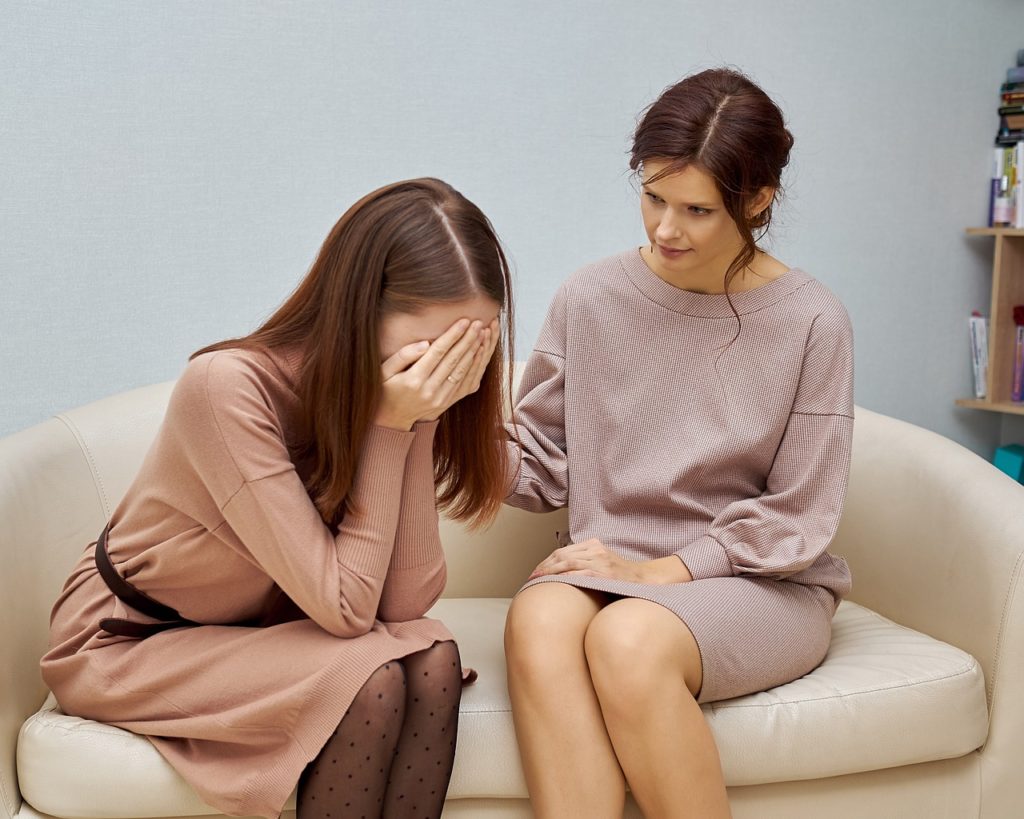 Jak zadbać o swoje zdrowie psychiczne? - kobieta pociesza kobietę płacząca na kanapie. 
