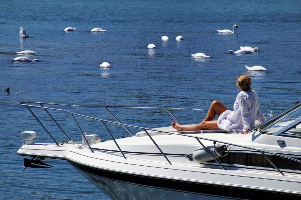 Jak osiągnąć work-life balance? - kobieta siedzi na rufie jachtu pływającego po jeziorze. 