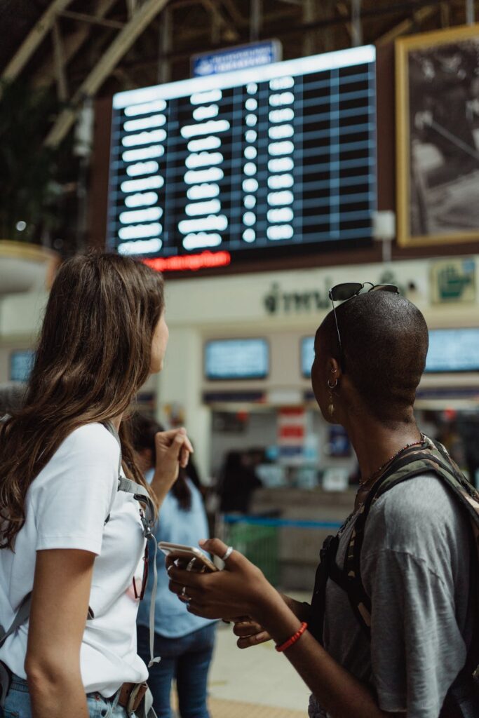 Odwołany lub opóźniony lot - czy jest szansa na rekompensatę? - ludzie na lotnisku patrzą na tablice z rozkładem lotów. 