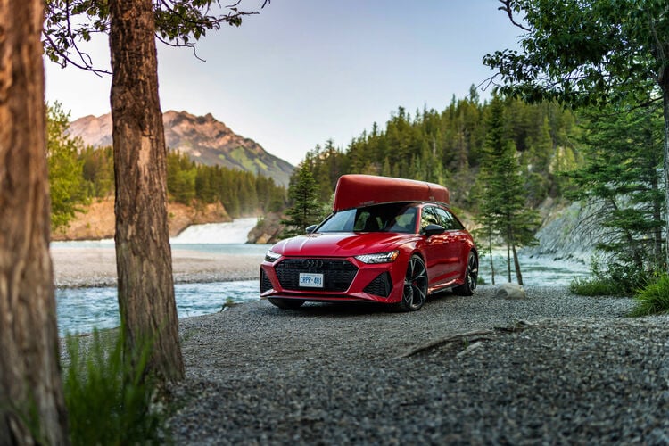 Fakty i ciekawostki o Audi RS 6 - czerwone auto stoi w lesie nad rzeką.