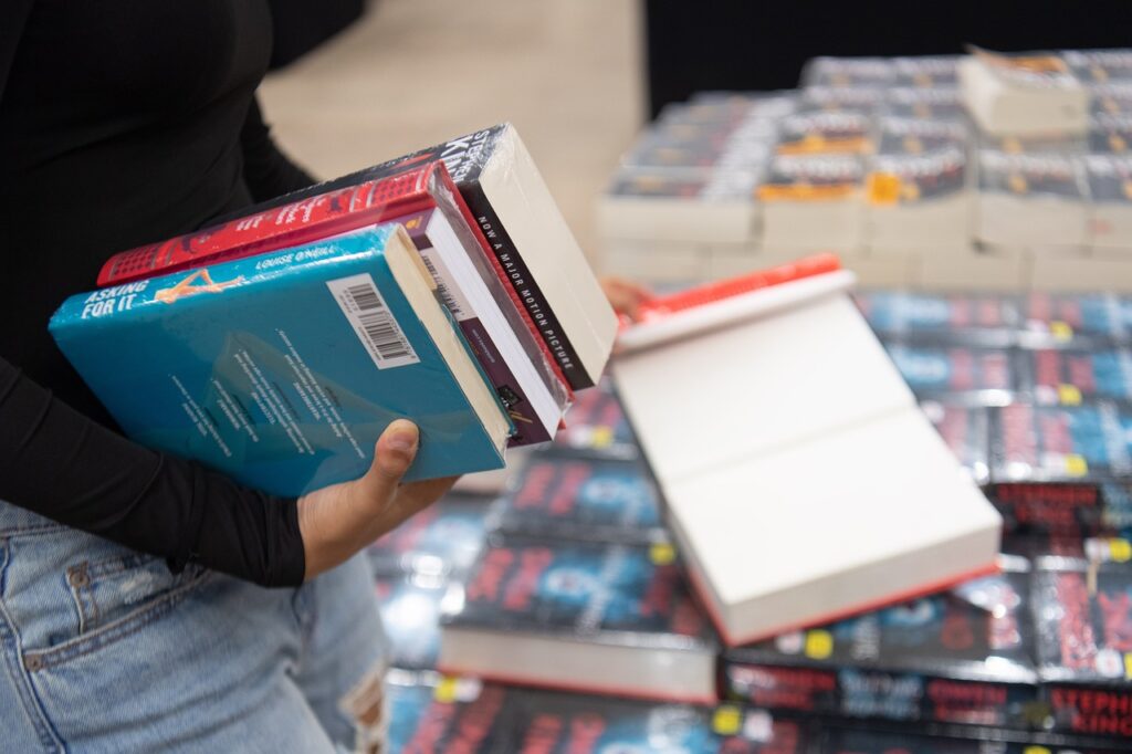 Dziś startują jesienne Targi Książki w Empiku - kobieta trzyma w reku kilka książek. 