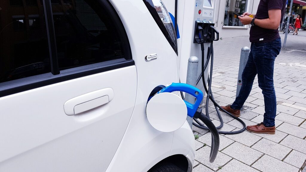 Ile za prąd w 2023 roku zapłaci posiadacz auta elektrycznego? - białe auto podczas ładowania elektrycznego.