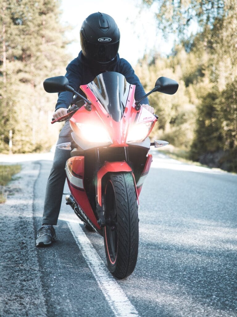 Na co zwrócić uwagę kupując używany motocykl? - mężczyzna siedzi na czerwonym motorze.
