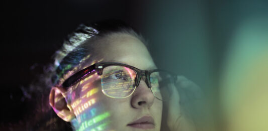 Kobieta w okularach, w których odbijają się cyfrowe dane